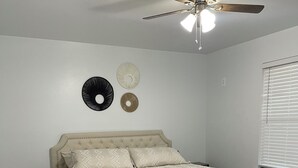 Une chambre à coucher avec un lit, un ventilateur de plafond et une table de chevet.