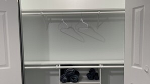Un dressing avec une porte-miroir, une tringle pour suspendre les vêtements et des étagères pour ranger les vêtements pliés.