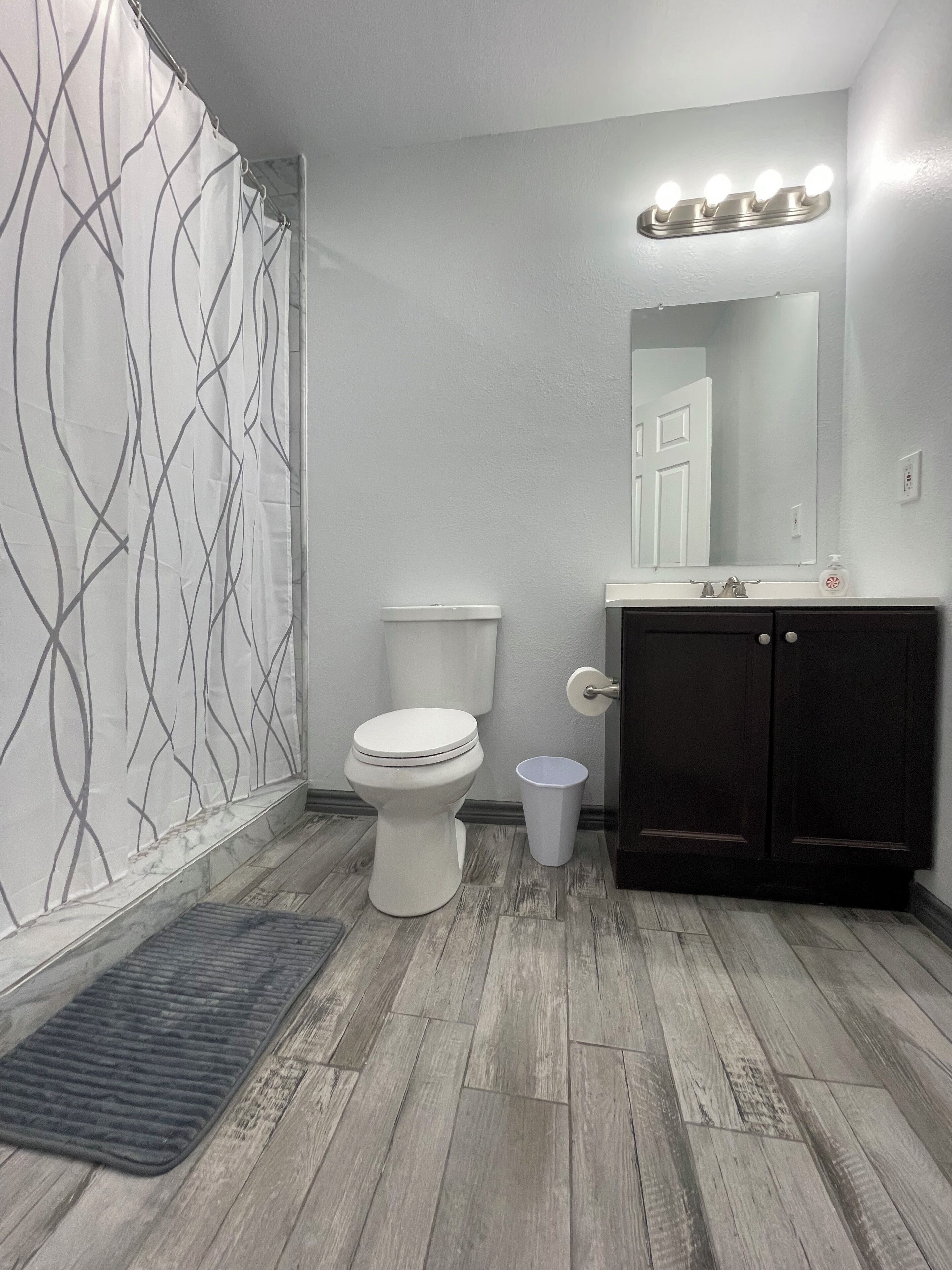 A bathroom with a toilet, a sink, a mirror, and a shower curtain.