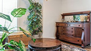 Une pièce avec une commode en bois, une table ronde et une plante en pot.