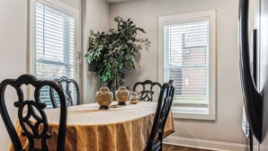 Une salle à manger avec une table ronde, des chaises noires, une plante et des vases décoratifs.