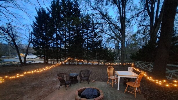 Un espacio al aire libre con sillas de mimbre, una mesa y una chimenea.