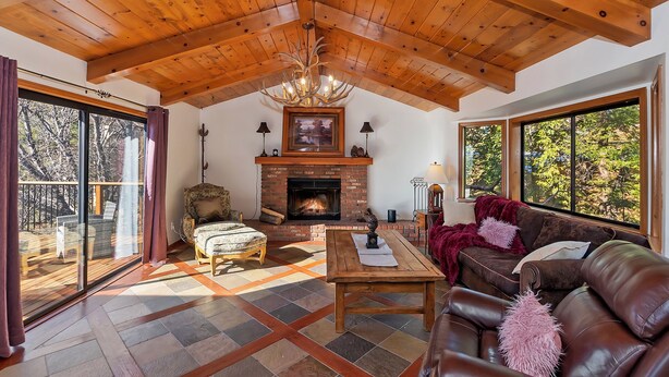 Un salón amplio con techo de madera, chimenea, ventana grande y una zona de estar acogedora.