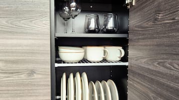 Un armario de cocina con estantes que contienen copas de vino, tazas, cuencos y platos.