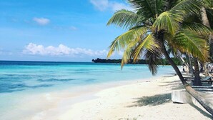 Una playa con agua turquesa cristalina, arena blanca y palmeras.
