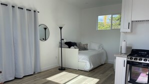 Une chambre à coucher de taille modeste, comprenant un lit, une lampe de chevet et une fenêtre donnant sur un paysage verdoyant.
