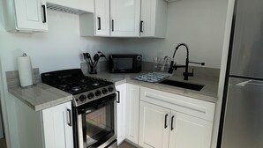 Une cuisine moderne avec des meubles blancs, un réfrigérateur en acier inoxydable, une cuisinière noire et un four à micro-ondes.