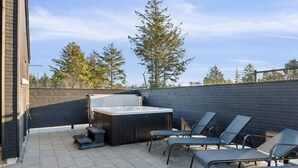 Une terrasse extérieure dotée d’un jacuzzi, de chaises longues et d’une clôture en bois.