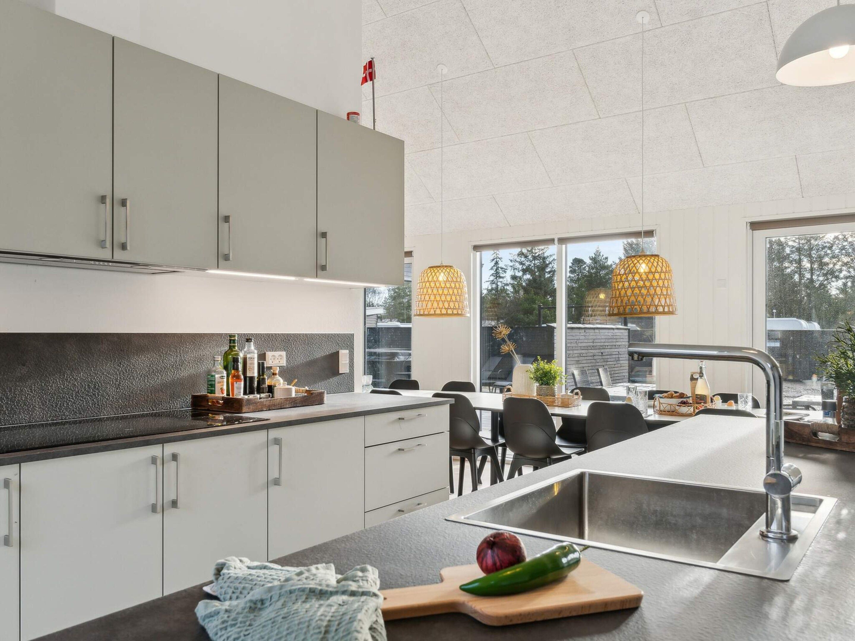 Una cocina moderna con armarios blancos, una isla grande con un fregadero y luces colgantes.