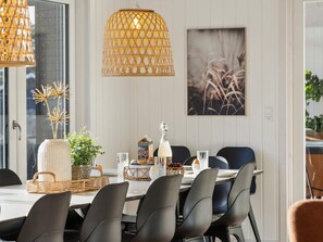 A dining area with a white table, black chairs, wicker baskets, and a hanging light fixture. - 5 Star Holiday Home in Vejers Strand (Vejers Strand)