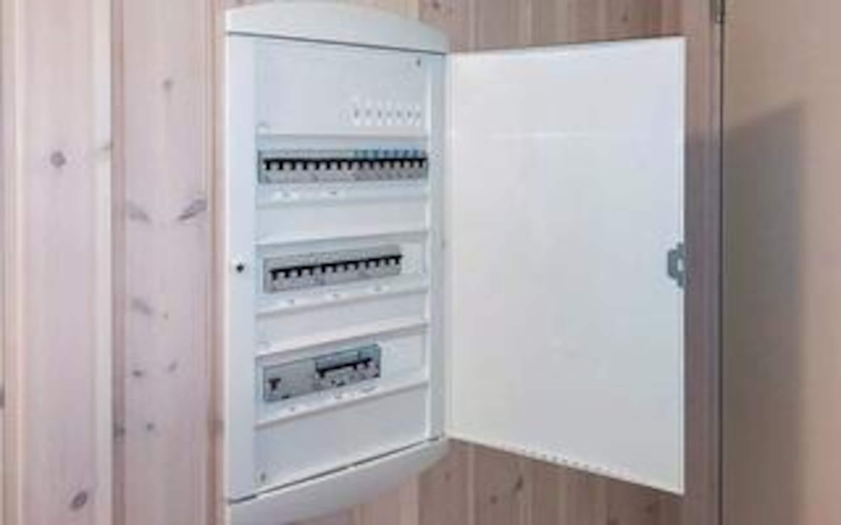 A white electrical panel with multiple circuit breakers and a door.