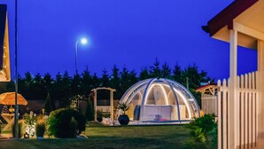 A dome-shaped structure with a transparent roof, surrounded by a white picket fence, and a street lamp in the background.