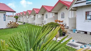A row of white cabins with red roofs and white picket fences.