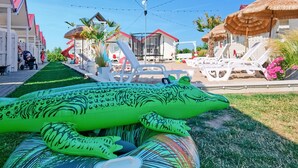 A pool area with inflatable toys, lounge chairs, and a building with a red roof.