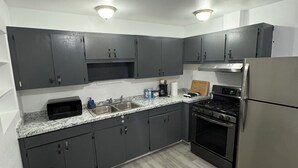 Una cocina moderna con armarios grises oscuros, un refrigerador de acero inoxidable, una estufa a gas y una encimera de granito.