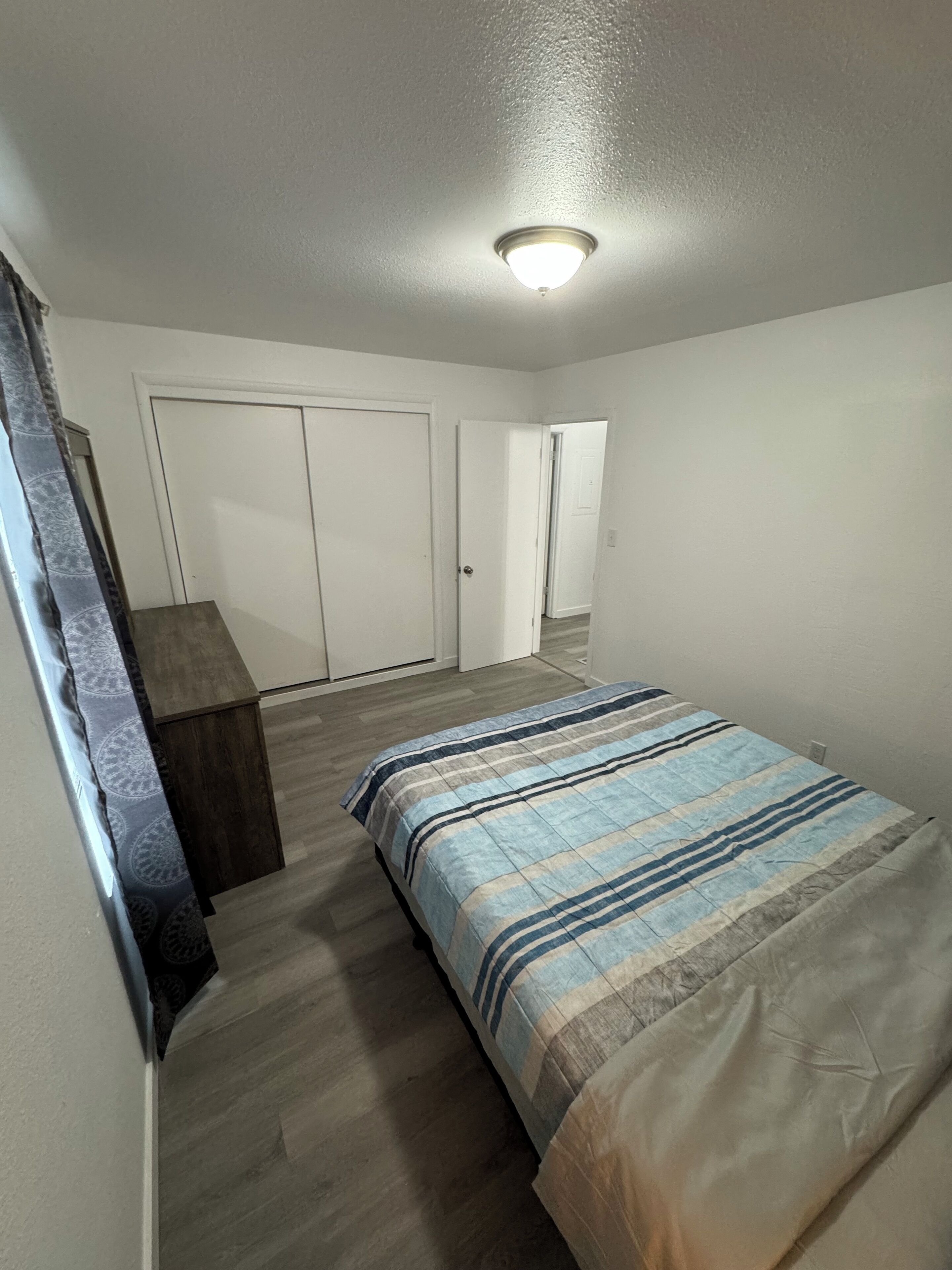 A bedroom with a bed, a wardrobe, and a door leading to another room.