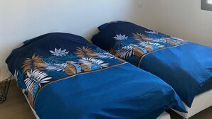 A bedroom with two beds, a hanging light fixture, and three framed pictures on the wall. - Villa relaxation (Narbonne)