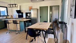 A modern kitchen with a wooden island, bar stools, and a dining table with chairs. - Villa relaxation (Narbonne)