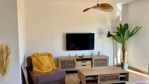 A modern living room with a sofa, coffee table, TV, and decorative plants. - Villa relaxation (Narbonne)