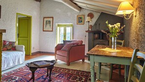 Uma sala de estar acolhedora com uma poltrona vermelha, uma mesa de jantar de madeira e uma porta verde.