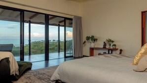 Une chambre avec un grand lit, une vue sur l’extérieur et une porte-fenêtre coulissante.