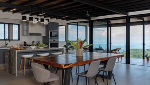 Une cuisine moderne dotée d’un grand îlot central, de tabourets de bar et offrant une vue sur l’océan.