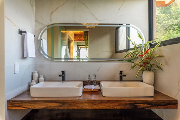 A bathroom with two white sinks, a large mirror, and a potted plant. - Lumina Valley View Monteverde (Monteverde)