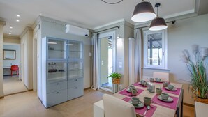Een moderne keuken met een eethoek, met een inbouwkast, een gedekte eettafel met kopjes en schotels, en een raam met uitzicht.