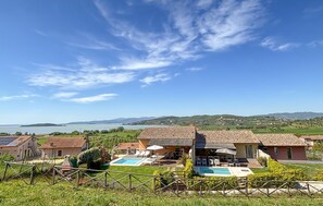 Eine Villa mit Swimmingpool, umgeben von üppiger Vegetation und Blick auf Meer und Hügel.