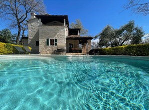 Un edificio in pietra con una piscina di fronte.