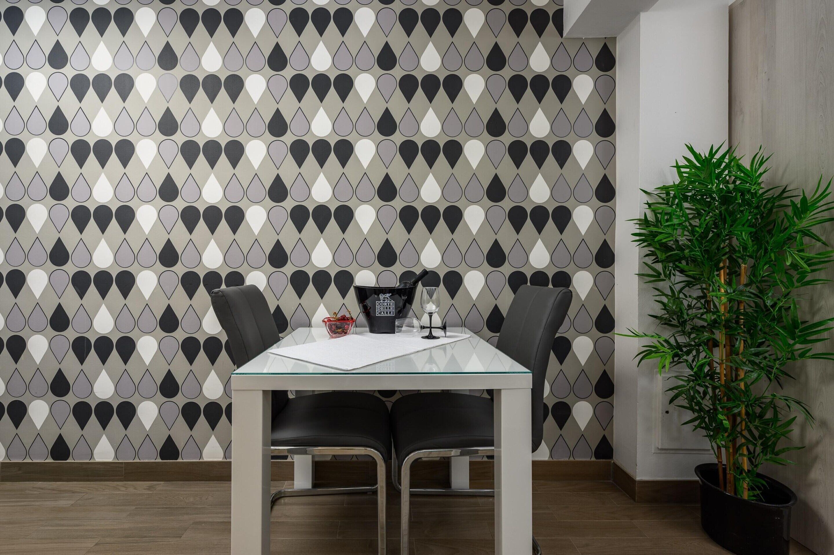 Ein Essbereich mit Tisch und Stühlen, einer Wand mit Muster und einem Blumentopf.