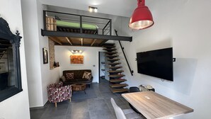 A compact living space with a loft bedroom, a staircase, a dining area, and a TV mounted on the wall. - Apartment With View (Porec)