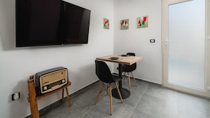A modern room with a flat-screen TV, a wooden table with two chairs, a vintage radio, and a door with frosted glass panels. - Apartment With View (Porec)