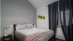 A bedroom with a bed, bedside lamps, a bedside table, a window with curtains, and three wall art pieces. - Apartment With View (Porec)