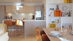 Una cocina moderna con una isla central, taburetes de bar y una mesa de comedor para dos.
