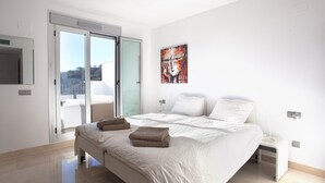 Un dormitorio moderno con una cama grande, un ventanal corredero a un balcón y un cuadro en la pared.