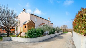 Une maison à deux étages avec une cabane en bois pour les enfants, une allée et une haie.