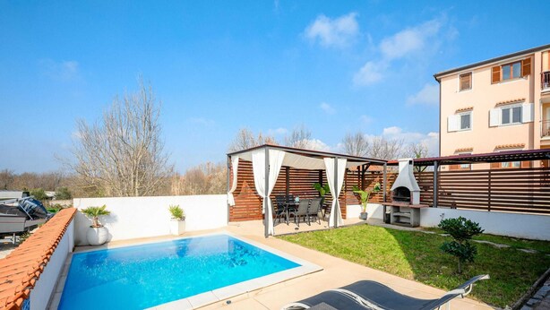 Un jardin avec une piscine, un espace salon extérieur et un coin barbecue.