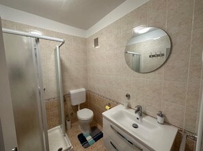 A bathroom with a shower, toilet, sink, and a mirror. - Comfortable Apartment With Terrace (Porec)