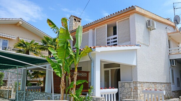 A two-story house with a stone facade, a balcony, and a covered porch area.