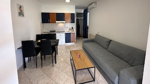A compact living space with a kitchenette, a dining area with a table and chairs, and a sofa.