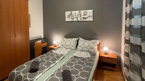 A bedroom with a bed, two bedside tables, a wardrobe, and a wall-mounted artwork.