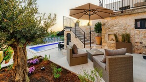 A patio area with outdoor furniture, a pool, and a stone wall. - Beautiful Apartment With View (Porec)