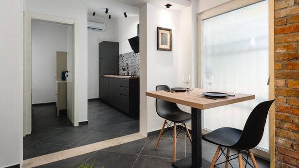 A modern kitchen with dark cabinets, a black countertop, and a window with a view. - Apartment With Scenic View (Porec)