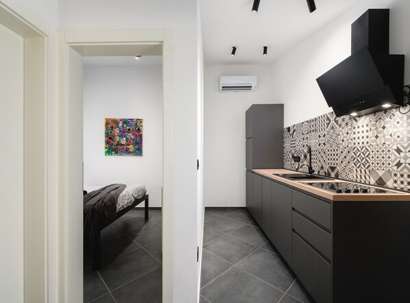 Una cucina moderna con una cappa aspirante nera, mobili grigi e piastrelle decorate.