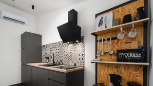 A modern kitchen with a black stove, grey cabinets, and a patterned backsplash. There are shelves with kitchen utensils and a coffee maker. - Apartment With Scenic View (Porec)