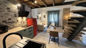 A modern kitchen with a red refrigerator, a dining area with a wooden table, and a spiral staircase leading to an upper level. - Apartment With Cozy Bedroom (Porec)