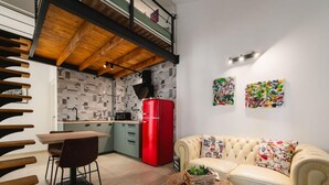A modern kitchen with a red refrigerator, a dining area with a wooden table and chairs, and a living area with a beige sofa and colorful cushions. - Apartment With Cozy Bedroom (Porec)