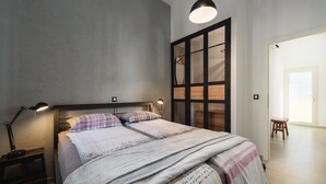 A neatly made bed with a headboard, a bedside lamp, and a hanging light fixture. - Apartment With Cozy Bedroom (Porec)