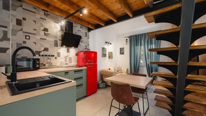 A modern kitchen with a built-in microwave, a red refrigerator, and a dining area with a wooden table and two chairs. - Apartment With Cozy Bedroom (Porec)